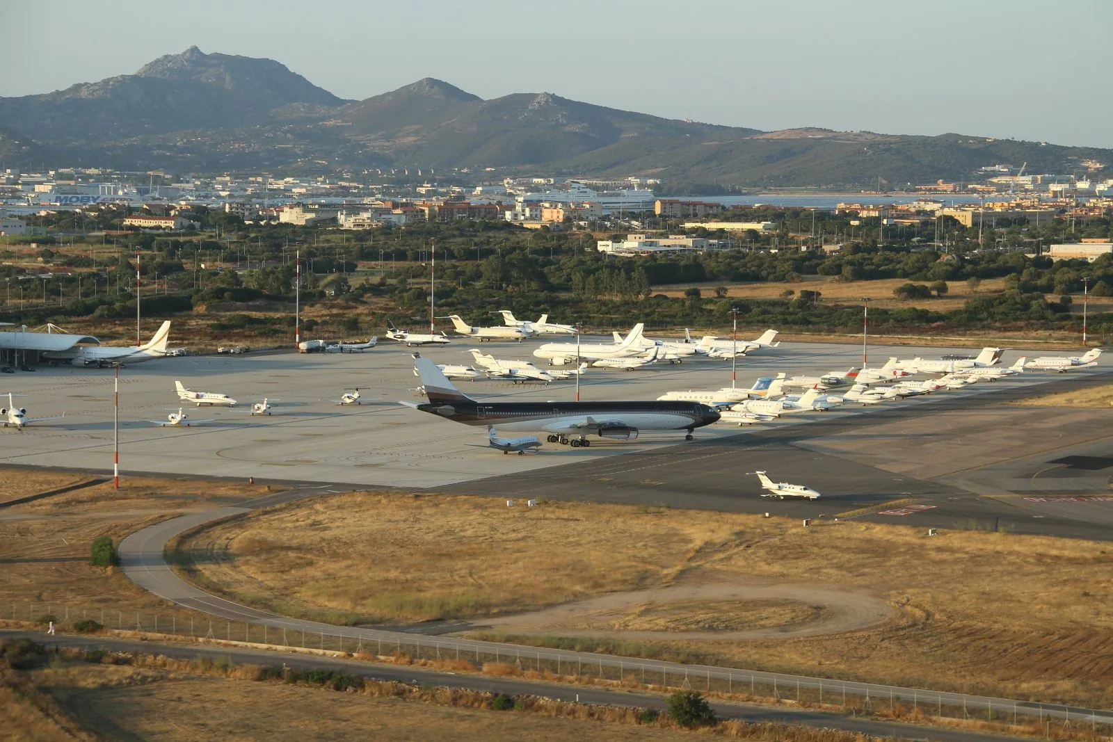Veduta dell'aeroporto di Olbia Costa Smeralda con gli aerei sul piazzale, la città e le colline sullo sfondo