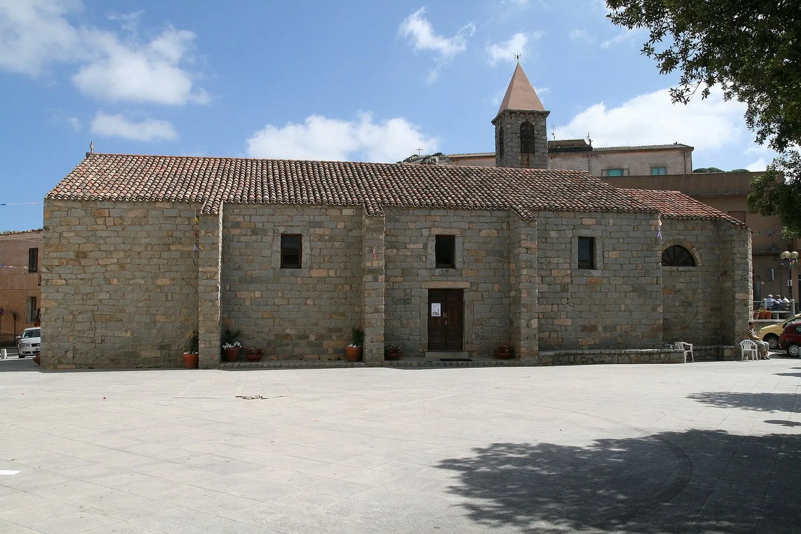 La chiesa della Santissima Trinità in granito, sulla piazza di Trinità d'Agultu, sotto un cielo estivo