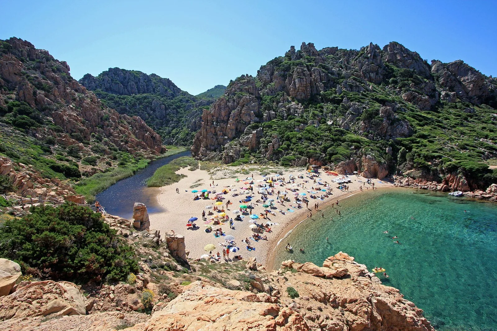 La spiaggia di Li Cossi a Costa Paradiso vista dall'alto, chiusa tra rocce rosse, con il piccolo rio e il mare turchese